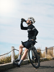 Obraz premium Man, break and drinking water with bicycle for hydration, rest and outdoor training or routine. Fitness, exercise and cyclist on mountain road with bike, h2o and health detox in workout recovery