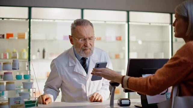 Apothecary customer showing mobile phone to man pharmacist at cashier closeup