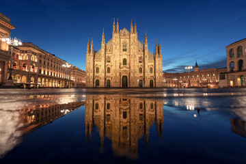 Fototapeta premium Illuminated Duomo di Milano and Galleria Vittorio Emanuele II with water reflection in Piazza del Duomo, Milan