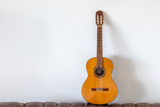 Classical Spanish guitar leaning against white wall with copy space