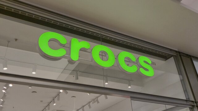 Vilnius Lithuania 09.05.2026 Crocs footwear store illuminated green logo in modern shopping mall international casual shoe brand retail storefront with contemporary commercial interior