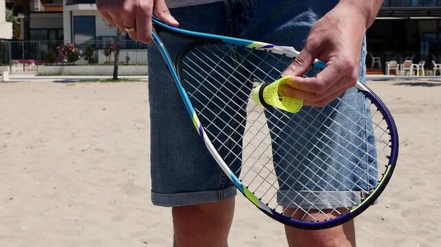 Close-up of speed badminton racket and shuttlecock on sandy beach, player practicing serve, fast-paced outdoor crossminton, active summer sport and fitness