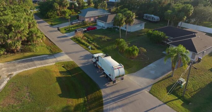 Trash truck picking up garbage bins on Florida city street curbside.