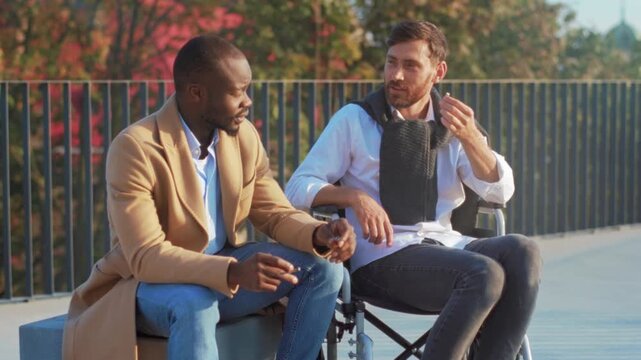 Diverse men converse on bench, Mentorship interaction unfolds amid fall foliage and urban park surroundings