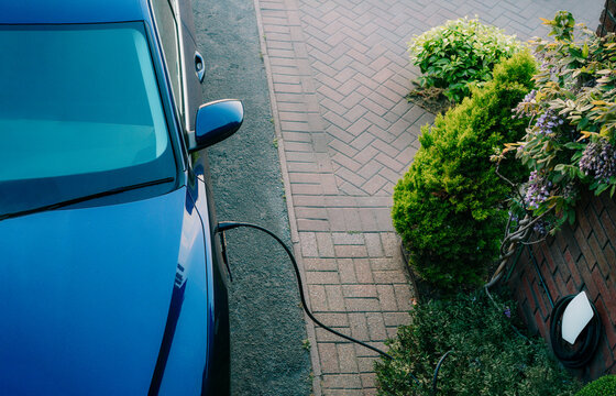 Top view electric car plugged into a charging station while parked in home. Residential EV Charging Station. Home EV Charging. Sustainable Power of a Wall-Mounted Charger. Future of Clean Transport.