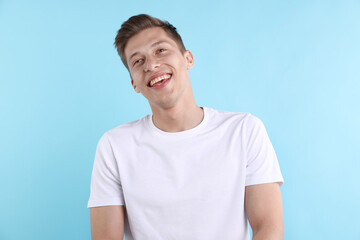 Obraz premium Young man laughing at joke on light blue background