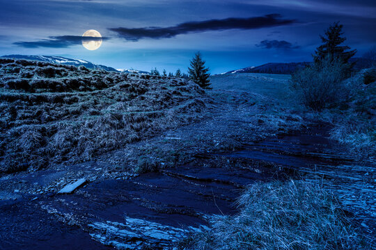 rural scenery in carpathian mountains at night. simple view of a countryside mountain landscape during springtime. full moon over brook near the grassy hills. mysterious fantasy concept