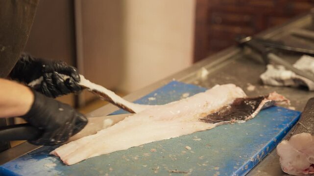 Cook Preparing Fresh Hake Fish in Restaurant Kitchen