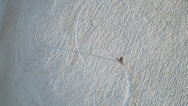 Aerial view of a lone skier crossing the snowy slopes of Le Colomby de Gex with curved tracks on the textured white surface in Echenevex, Auvergne-Rhone-Alpes, France.