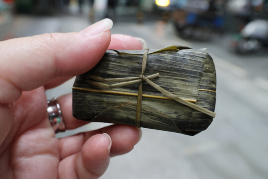 Hand holding a Dongba (Frozen Rice cake) made with indica rice and wrapped with bamboo leaf is a unique local snack at Leshan, Sichuan Province of China