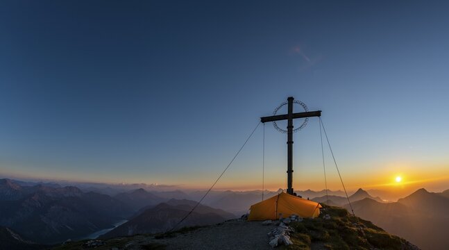 Sunset over Lechtal mountains, in the foreground summit cross of the Geierkopf with tent, Reutte, Ammergau Alps, Tyrol, Austria