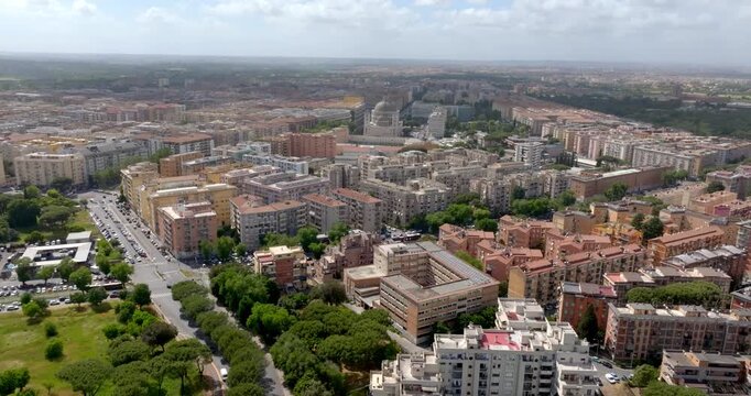 Panoramic aerial view of the Tuscolano district in Rome, Italy, showing a high density of residential buildings and urban greenery near Cinecitt&agrave;, under a wide Mediterranean horizon and clear sky.
