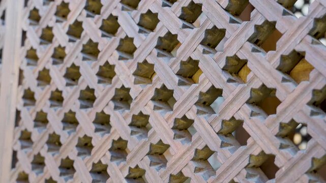 Close-up of a traditional carved wooden lattice window with intricate geometric patterns. Detailed craftsmanship of an ornamental oriental screen, showcasing cultural architectural heritage