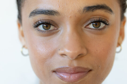 African American woman facing camera in studio wearing gold hoops nose stud mascara glossy lips