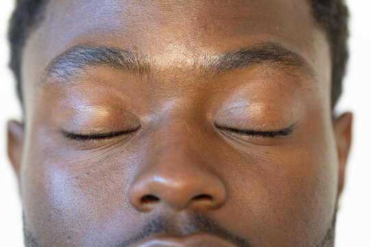 African American male posing with closed eyelids in studio closeup showing skin texture and stubble
