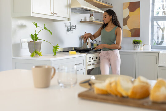 African American woman in her 20s stirring food on stovetop at home with spatula, copy space