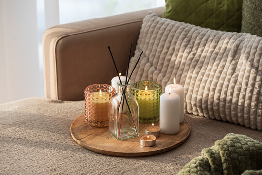 Candles and Reed Diffuser on Wooden Tray. Cozy Home Decor lifestyle with Cushions