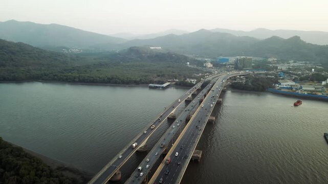 Aerial drone view of the Vasai Creek Bridge in Mumbai, India, spanning across the water and connecting key suburban regions. The scene captures vehicles moving along the bridge.