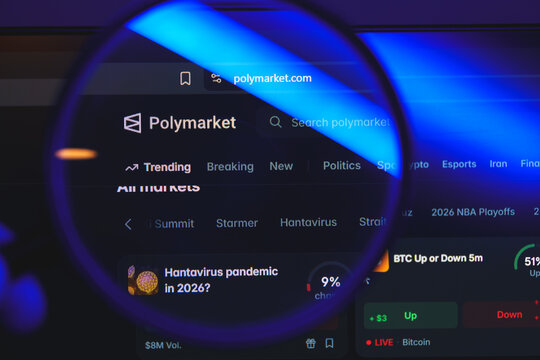 Polymarket website interface viewed through magnifying glass, decentralized prediction market platform for betting on politics, crypto, and global events concept