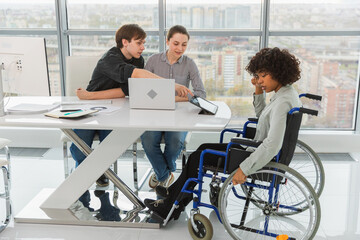 Teamwork brainstorm. Diverse multiracial colleagues woman in chair for people with disability working together. Group of people sitting in creative office discussing business. Young professional team © Юлия Завалишина