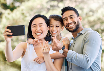 Fototapeta premium Parents, child and outdoor with peace sign for selfie, travel memory and bonding on summer holiday. Asian family, excited and photography in park for vacation blog, love and heart emoji with daughter