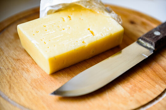 Spoiled cheese with mold on wooden cutting board.