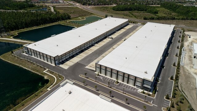 Aerial view of large modern industrial warehouses with white rooftops and retention ponds near Saint Johns Parkway in World Golf Village, Florida, United States.