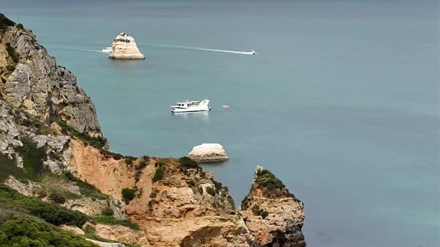 Breathtaking video captured from the iconic Viewpoint Praia do Camilo in Lagos, Portugal, showcasing dramatic golden cliffs, crystal clear turquoise waters and a popular tourist destination