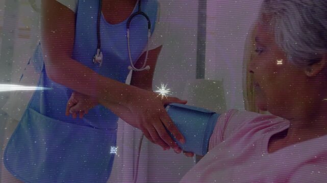 Caregiver holding blue BP cuff, fitting onto seated senior patient's arm, adjusting for BP check