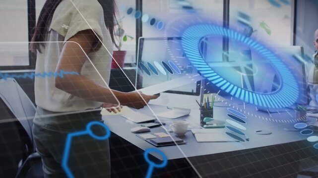 Businesswoman spotting monitor charts passing papers to seated man while HUD highlighting data