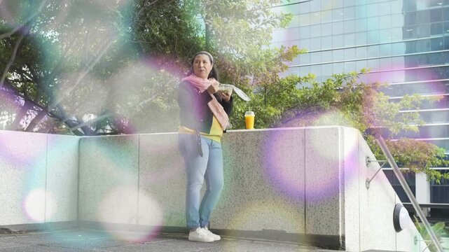 Woman lifting takeout and eating lunch on terrace, light flare moving across for food marketing