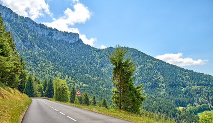 Obraz premium Landscape, mountain and road with sign in nature for travel, tourist destination and journey outdoor. Empty, background and street with scenic route, highway and space for vacation, trip and holiday