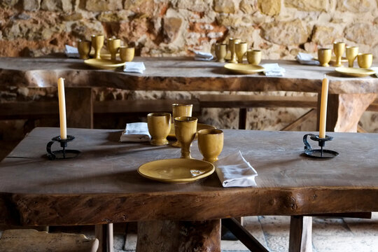 Historic dining table with brass goblets in a rustic stone interior