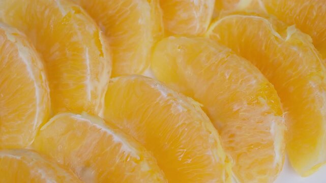 Fresh fruit segments glistening against white background for advertising. Vivid citrus photo capturing overlapping orange slices with detailed textures and vibrant colors