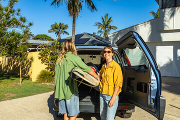 Friends packing surfboard in suv for summer surf trip