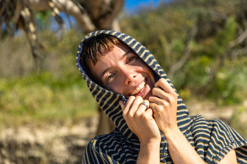 Fototapeta premium Woman smiling in striped poncho after surfing