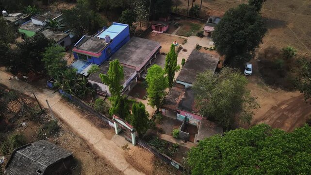 Aerial drone view of a government school located in the rural region of Odisha, India. The scene captures simple school buildings surrounded by greenery and open land.