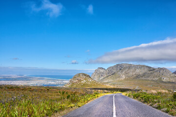 Obraz premium Travel, blue sky and road on mountain to ocean, tourist destination and journey outdoor. Landscape, background and street with scenic route, highway and space for vacation, trip and holiday to coast