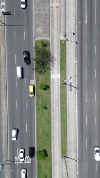A massive traffic jam clogs the city street in an aerial drone view, with cars passing by as if in a video game