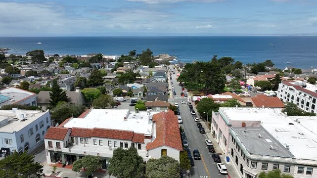 Pacific Grove, California, USA - Cinematic Drone Side Movement Above Lighthouse Avenue with Lovers Point Park and Monterey Bay in the Distance