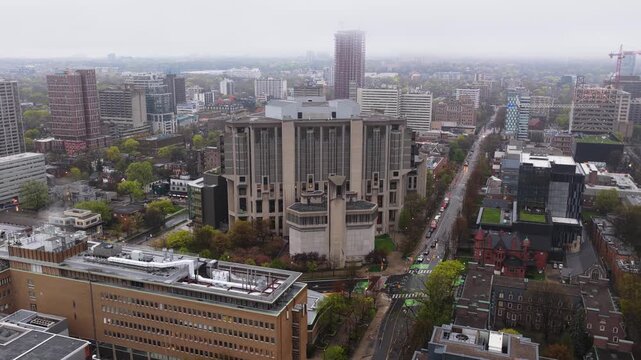 Gray foggy morning over University of Toronto Robarts Library, traffic moving along St. George Street and modern brutalist architecture prominent against city skyline