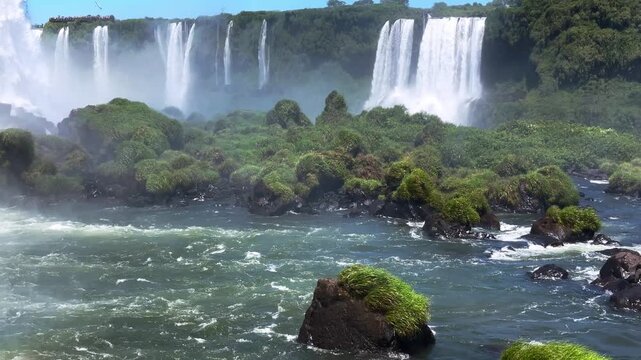 Panoramic view of the majestic Iguazu Falls in Foz do Iguacu, Brazil, showing powerful waterfalls cascading into the river surrounded by lush tropical rainforest vegetation