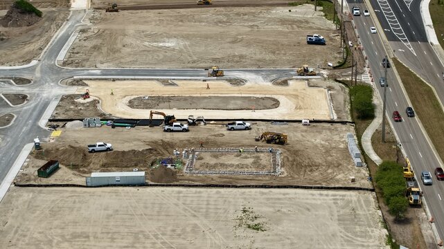 Aerial view of Foundry Lane construction site with heavy machinery, workers, and dirt ground in World Golf Village, Florida, United States.