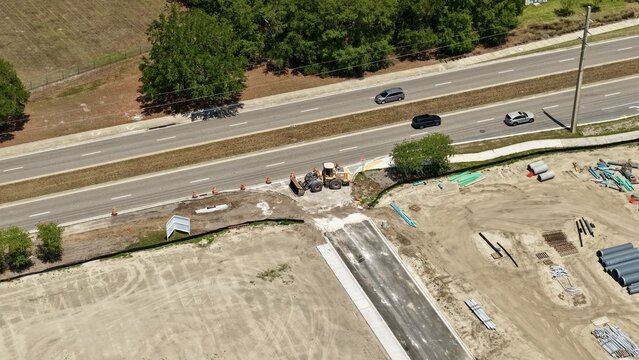 Aerial view of the Foundry Lane construction site with a front loader and building materials next to a highway in World Golf Village, Florida, United States.