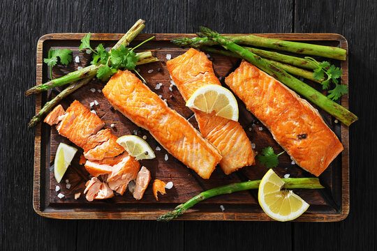 fried salmon with asparagus and lemon on a board
