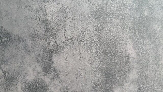 Grey plaster cottage wall close-up with mottled speckled finish, subtle patina and porous grain. Rough stucco texture blends