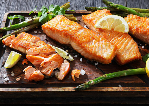 fried salmon with asparagus and lemon on a board