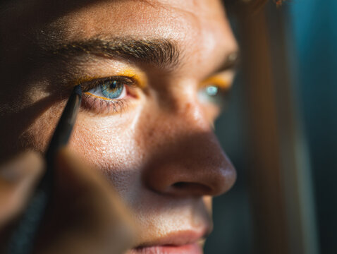 Close-up of person applying eyeliner in natural window light