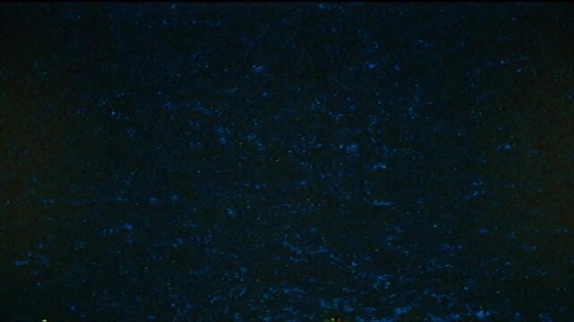 Abstract grainy noise pattern with blue flickering artifacts on dark background in cinematic style.