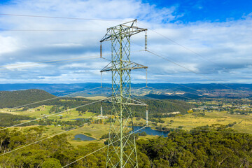 Obraz premium Aerial photograph of a large electrical transmission tower and power grid running through a forest and valley in the Blue Mountains in New South Wales, Australia